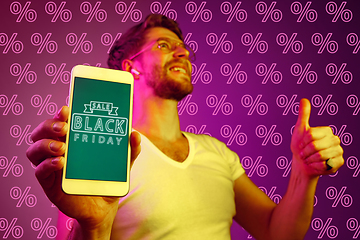 Image showing Portrait of man showing screen of mobile phone, black friday