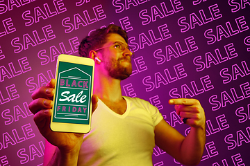 Image showing Portrait of man showing screen of mobile phone, black friday