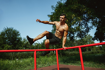 Image showing Young muscular man while doing his workout outside at playground