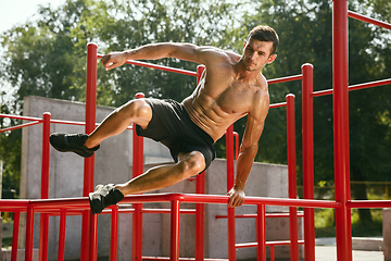 Image showing Young muscular man while doing his workout outside at playground