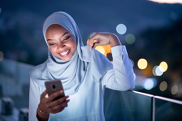 Image showing Young Muslim woman on  street at night using phone