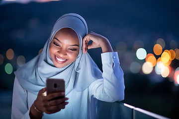 Image showing Young Muslim woman on  street at night using phone