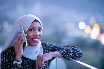 Image showing Young Muslim woman on  street at night using phone