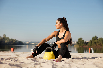 Image showing Young healthy female athlete doing workout at the beach