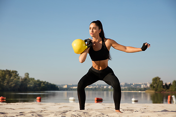 Image showing Young healthy female athlete doing workout at the beach