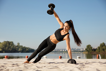 Image showing Young healthy female athlete doing workout at the beach