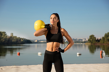 Image showing Young healthy female athlete doing workout at the beach