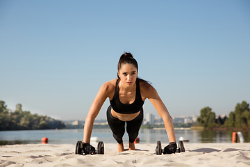 Image showing Young healthy female athlete doing workout at the beach