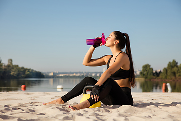 Image showing Young healthy female athlete doing workout at the beach