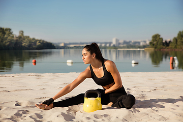 Image showing Young healthy female athlete doing workout at the beach