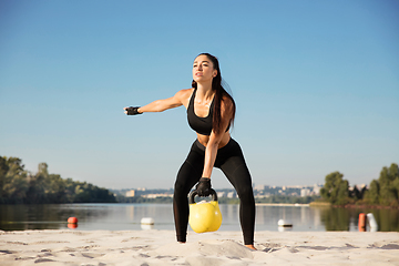 Image showing Young healthy female athlete doing workout at the beach