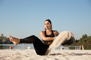 Image showing Young healthy female athlete doing workout at the beach