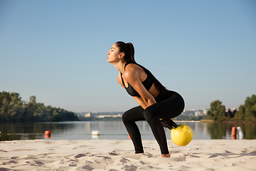 Image showing Young healthy female athlete doing workout at the beach