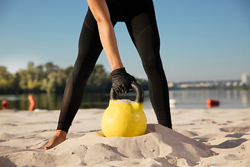 Image showing Young healthy female athlete doing workout at the beach