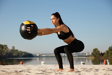 Image showing Young healthy female athlete doing workout at the beach