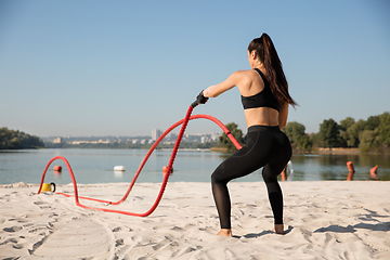 Image showing Young healthy female athlete doing workout at the beach