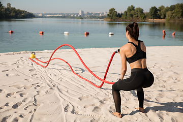 Image showing Young healthy female athlete doing workout at the beach