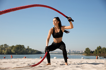 Image showing Young healthy female athlete doing workout at the beach