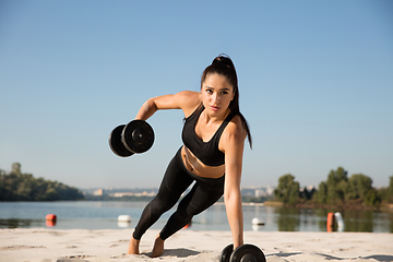 Image showing Young healthy female athlete doing workout at the beach