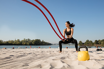 Image showing Young healthy female athlete doing workout at the beach