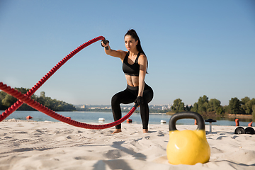 Image showing Young healthy female athlete doing workout at the beach