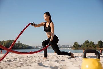 Image showing Young healthy female athlete doing workout at the beach