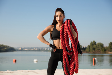 Image showing Young healthy female athlete doing workout at the beach