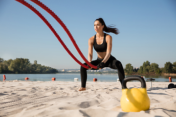 Image showing Young healthy female athlete doing workout at the beach