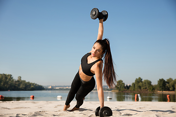 Image showing Young healthy female athlete doing workout at the beach