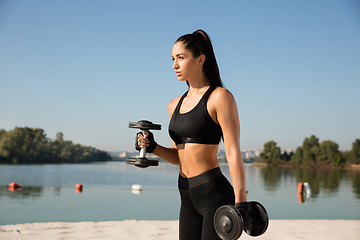 Image showing Young healthy female athlete doing workout at the beach