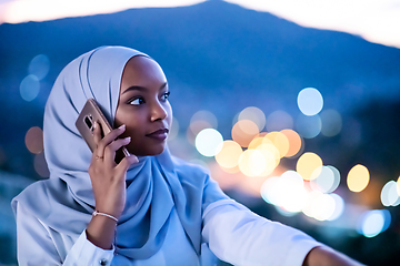 Image showing Young Muslim woman on  street at night using phone