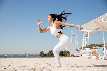 Image showing Young healthy female athlete doing workout at the beach