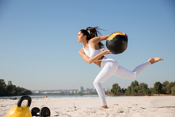 Image showing Young healthy female athlete doing workout at the beach