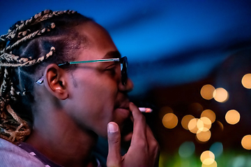 Image showing african american man smoking cigarette  at night