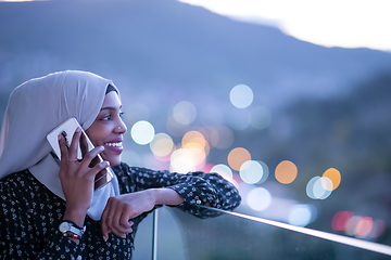 Image showing Young Muslim woman on  street at night using phone