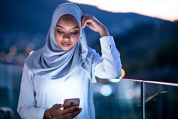 Image showing Young Muslim woman on  street at night using phone