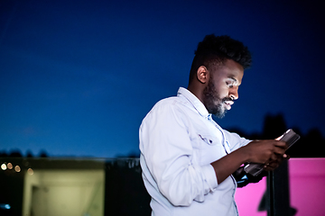 Image showing Young  Afro man on street at night using tablet computer