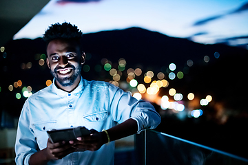 Image showing Young  Afro man on street at night using tablet computer