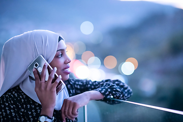 Image showing Young Muslim woman on  street at night using phone