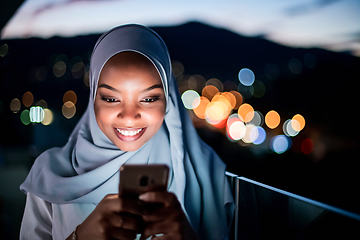 Image showing Young Muslim woman on  street at night using phone