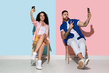 Image showing Young emotional man and woman on pink and blue background