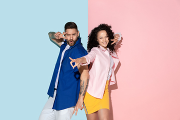 Image showing Young emotional man and woman on pink and blue background