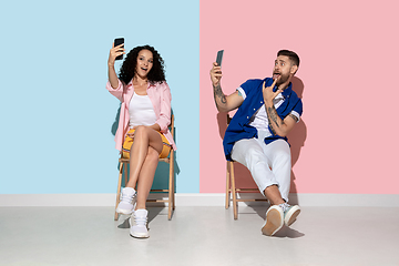 Image showing Young emotional man and woman on pink and blue background