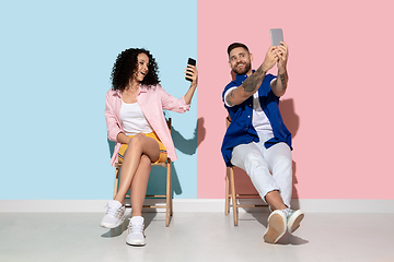 Image showing Young emotional man and woman on pink and blue background