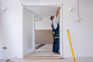 Image showing carpenters installing glass door with a wooden frame