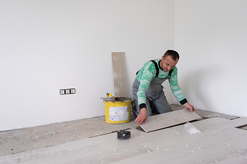 Image showing worker installing the ceramic wood effect tiles on the floor