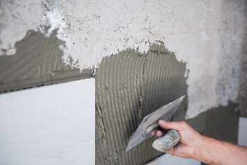 Image showing worker installing big ceramic tiles