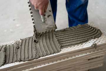 Image showing worker installing the ceramic wood effect tiles on the floor