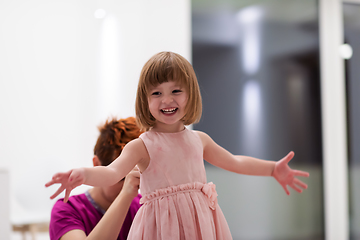 Image showing young mother helping daughter while putting on a dress