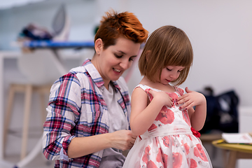 Image showing mother helping daughter while putting on a dress